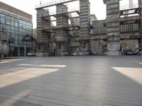 large empty building with scaffolds near the buildings in a public plaza area