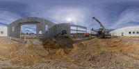 a pair of construction trucks are moving around an empty building site with other trucks on the side