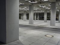 a tiled walkway is in a very large, empty building with concrete flooring and exposed ceiling