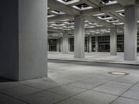 a tiled walkway is in a very large, empty building with concrete flooring and exposed ceiling