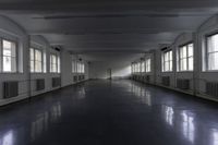 an empty building with some windows and a long corridor that is dark gray with lots of lights