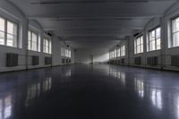 an empty building with some windows and a long corridor that is dark gray with lots of lights