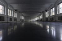 an empty building with some windows and a long corridor that is dark gray with lots of lights