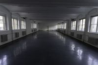 an empty building with some windows and a long corridor that is dark gray with lots of lights