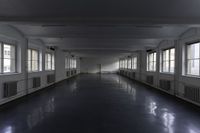 an empty building with some windows and a long corridor that is dark gray with lots of lights