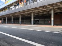 an empty bus stop at the side of a street in a city area with buildings behind it