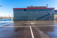 an empty car park in front of a brick building with windows on both sides, and a sign warning of what to do before