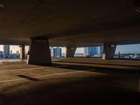 an empty car park under a highway with tall buildings in the background and a person standing on one side