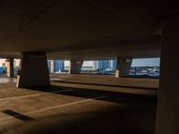 an empty car park under a highway with tall buildings in the background and a person standing on one side