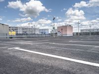 empty car parking lot with parking meters, clouds and buildings in the background and buildings under construction