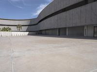 a view of an empty cement building from a parking lot with lots of parked cars