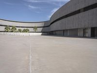 a view of an empty cement building from a parking lot with lots of parked cars