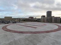 an empty circular parking lot with some buildings and clouds in the background in front of it