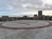 an empty circular parking lot with some buildings and clouds in the background in front of it