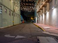 empty city alley with a row of buildings lit up with string lights at night time