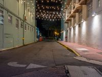 empty city alley with a row of buildings lit up with string lights at night time