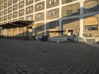 the empty city block of an old industrial area with a bench, trashcan and dog looking out