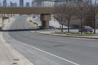 a city highway that looks empty with some cars on it and buildings in the background