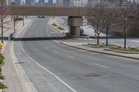 a city highway that looks empty with some cars on it and buildings in the background