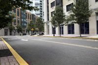 empty city street next to a large building with a yellow sign on one corner and street marked with white lines
