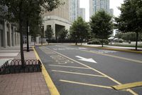 empty city street next to a large building with a yellow sign on one corner and street marked with white lines
