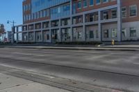 empty city road beside an apartment building with large windows and plants growing on the side