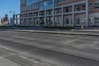 empty city road beside an apartment building with large windows and plants growing on the side