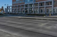 empty city road beside an apartment building with large windows and plants growing on the side