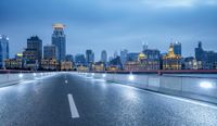 an empty city road in front of a skyline with buildings at dusk in shanghai, china