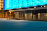 street scene with empty city sidewalk and brightly lit building at night with no cars in front