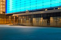 street scene with empty city sidewalk and brightly lit building at night with no cars in front