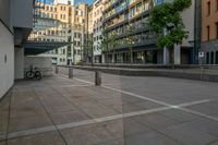 a parked bicycle sits in an empty city square on a sunny day from the ground to the right