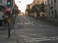 the view from the crosswalk of an empty city street in the afternoon time with a green light