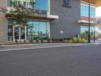 an empty city street in front of the entrance of an airport with glass windows and signage