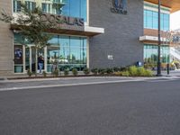 an empty city street in front of the entrance of an airport with glass windows and signage