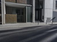 a city street with no cars passing by an empty building and a motorcycle parked next to it