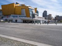 an empty city street with the buildings in the background behind it in front of an orange building