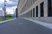 an empty city street with buildings along both sides of it and grass on the sidewalk