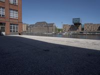 the city street is empty in the daylight time, and has buildings near it with water nearby