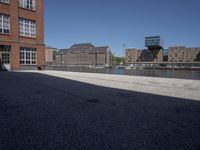 the city street is empty in the daylight time, and has buildings near it with water nearby