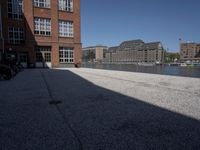 the city street is empty in the daylight time, and has buildings near it with water nearby