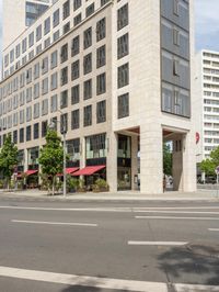 an empty city street is lined with tall buildings and cars in a traffic circle on a sunny day