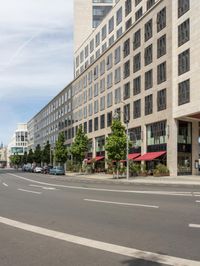 an empty city street is lined with tall buildings and cars in a traffic circle on a sunny day