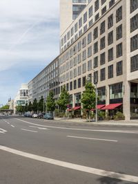 an empty city street is lined with tall buildings and cars in a traffic circle on a sunny day