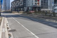 the empty street is lined with buildings in the background of a cityscape and a bicycle lane