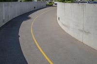 the empty street is lined with concrete walls as cars are parked on both sides of the road