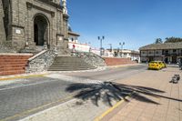 the city street is empty with a yellow car parked in front of the church as well