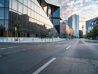 an empty street with some buildings in the background on a city street during sunset,