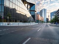 an empty street with some buildings in the background on a city street during sunset,