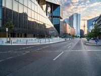 an empty street with some buildings in the background on a city street during sunset,